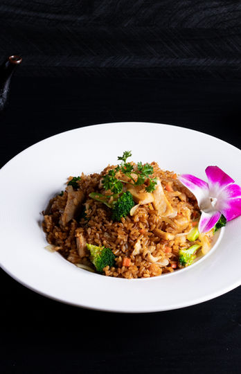 Fried rice dish on white plate with pink flower, with edamame, and tea