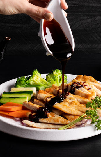 Sauce pouring on food with vegetables on plate, Sakana cuisine.